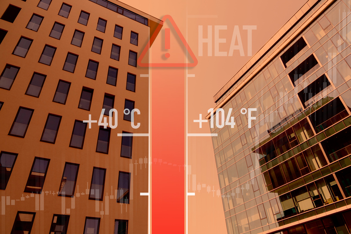 Graphic of a thermometer with high temperature reading against a blurred city building during a summer heatwave
